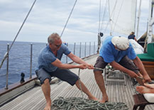 Zwei Männer ziehen an den Schoten auf einem Segelschiff