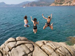 Mädchen springen von einer Klippe ins Meer