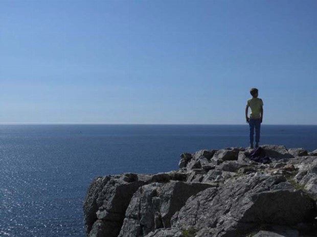 Junge genießt die Aussicht auf einer Klippe hoch über dem Atlantik