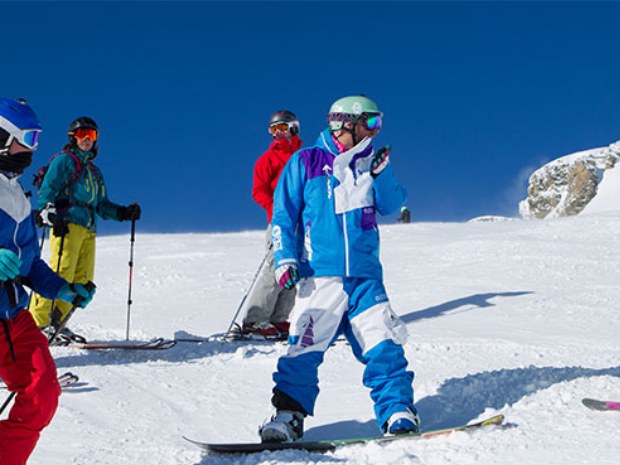 Ski- und Snowboardfahrer auf der Piste im Sonnenschein im Skiurlaub in Crans Montana