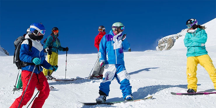 Ski- und Snowboardfahrer auf der Piste im Sonnenschein im Skiurlaub in Crans Montana