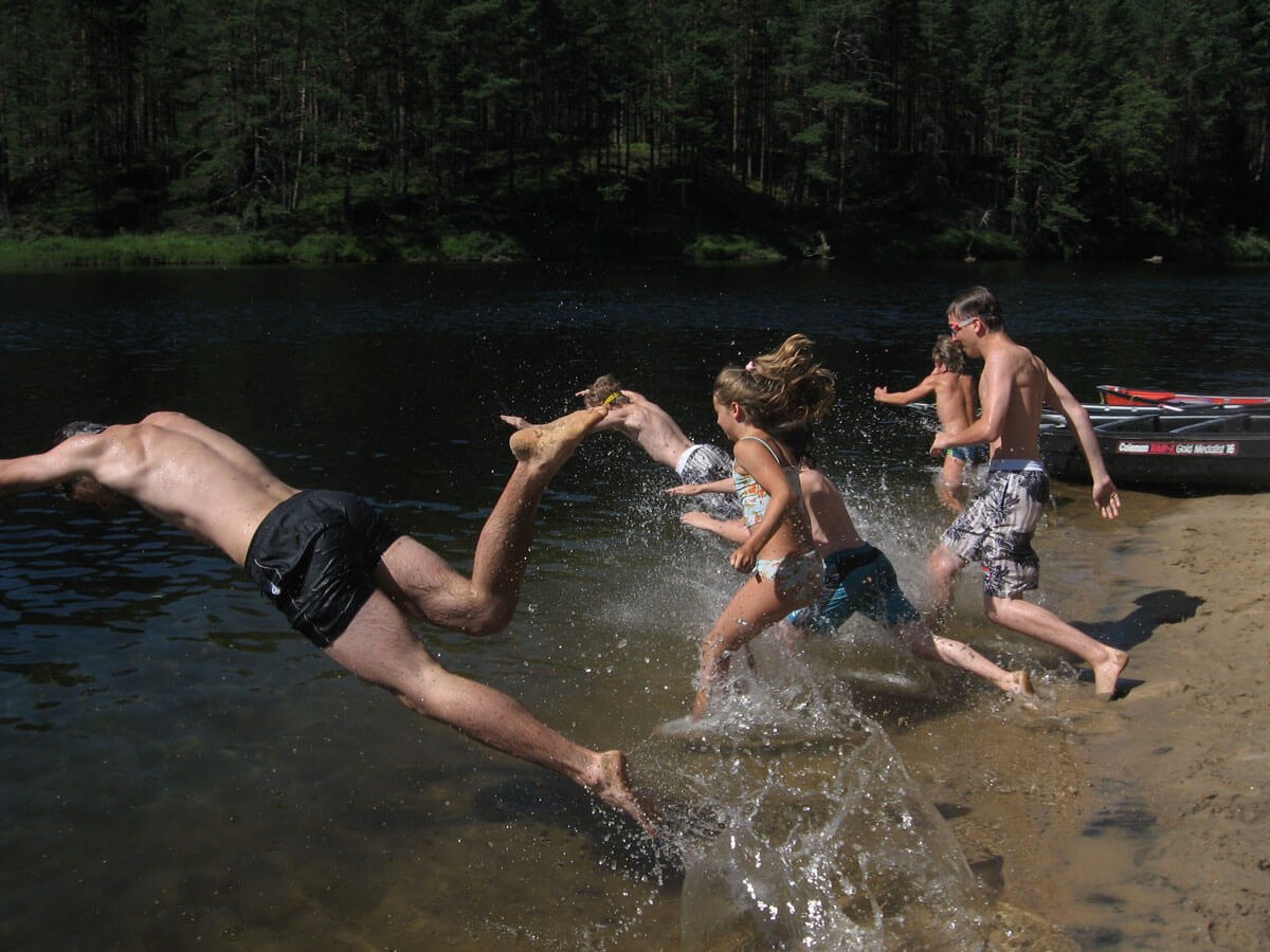 Kinder rennen in das Wasser des See. 