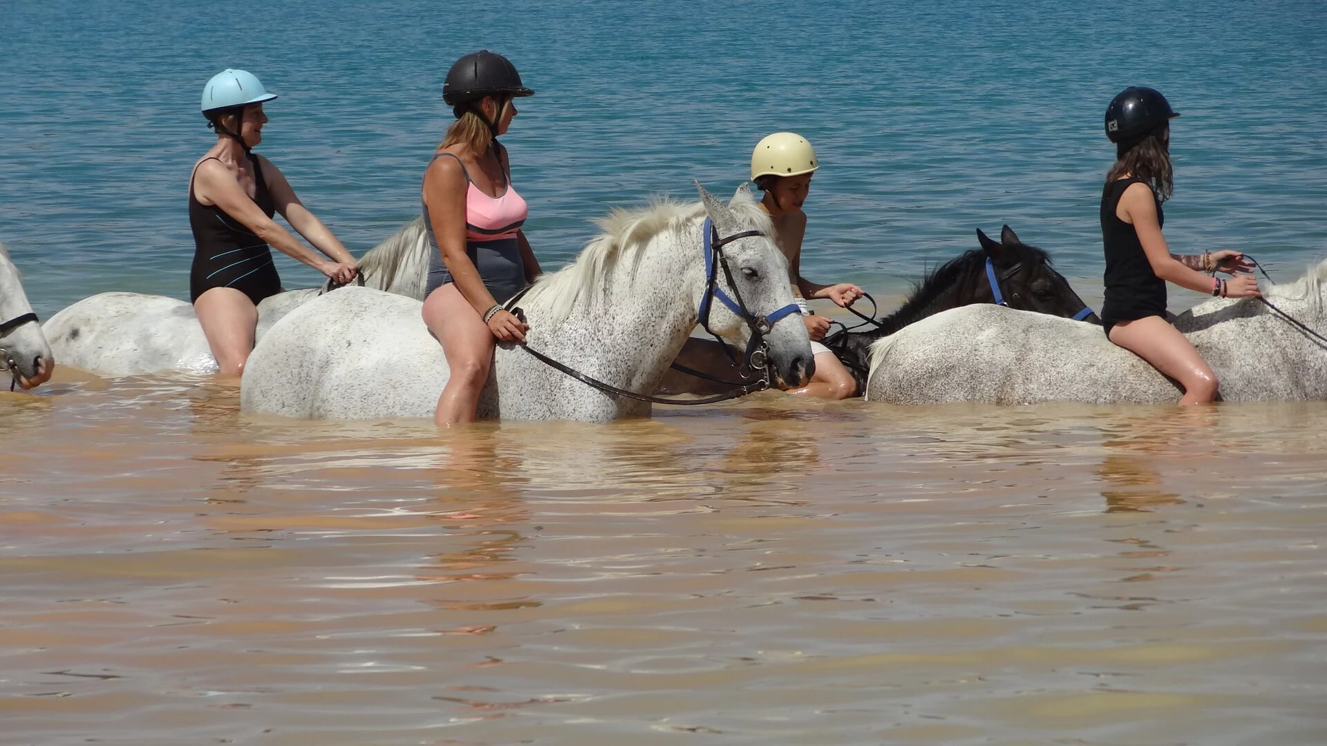 Reiter auf Pferden reiten durch den Lac de Ste. Croix. Das Wasser reicht bis zu den Knien.