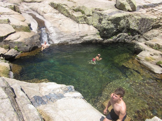 Ein Mann schwimmt in einer großen Gumpe im Gebirgsbach auf Korsika
