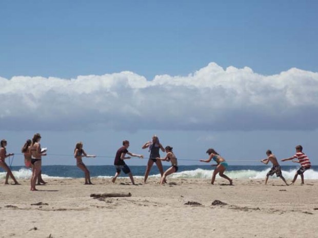 Teenager messen ihre Kräfte beim Tauziehen am Strand