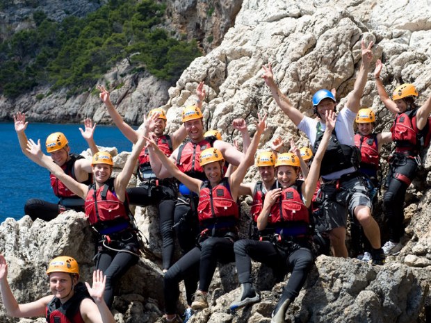 Canyoninggruppe sitzen freudestrahlend auf einem Felsen in Spanien