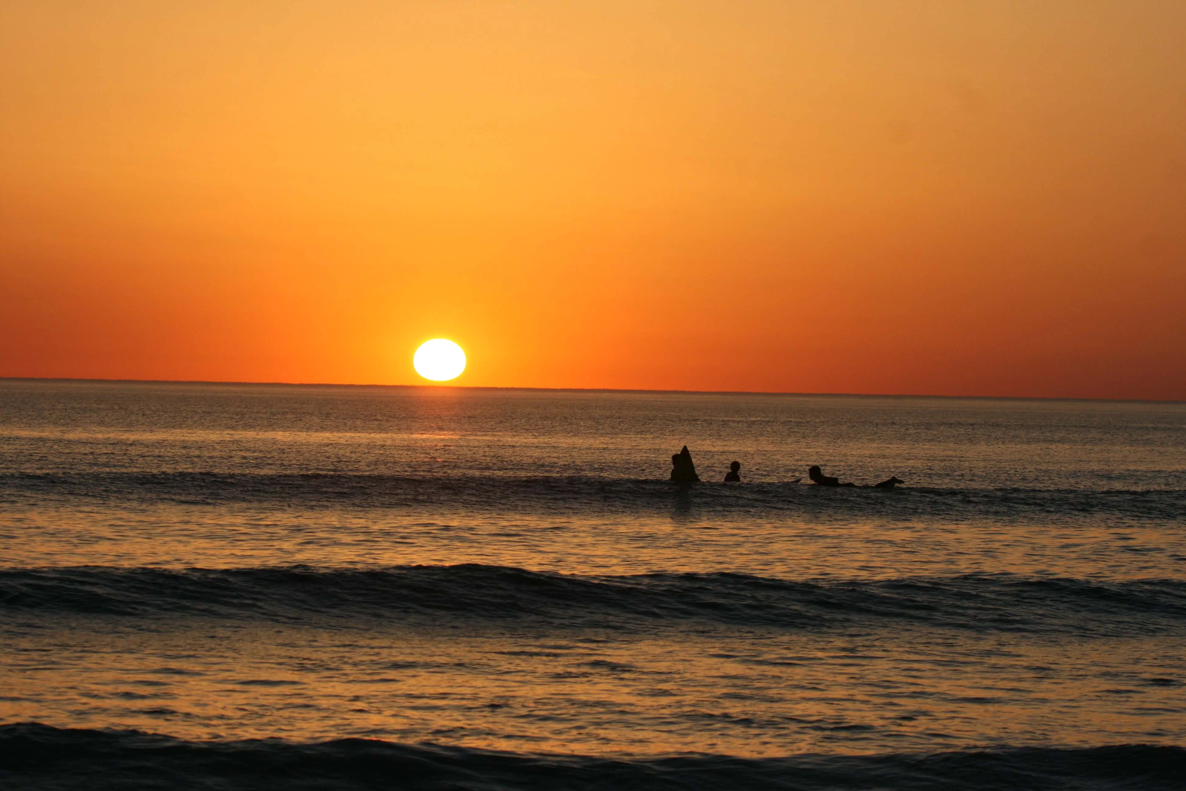 Die letzten Surfer surfen im Sonnenuntergang im Atlantik