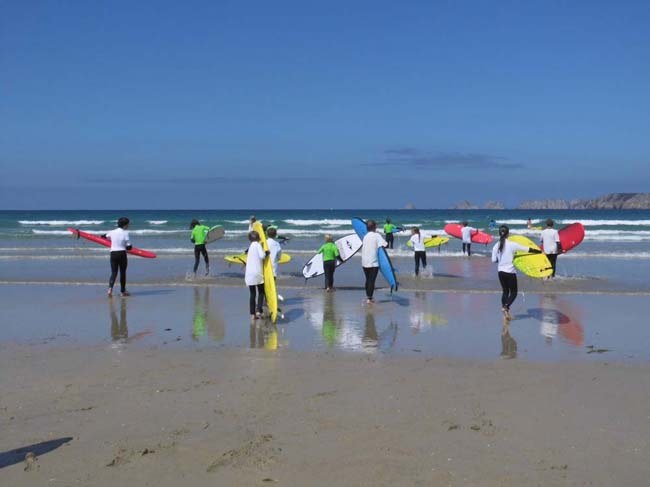Teenager beim Surfkurs. Es geht in die Wellen am Strand im Familiencamp.