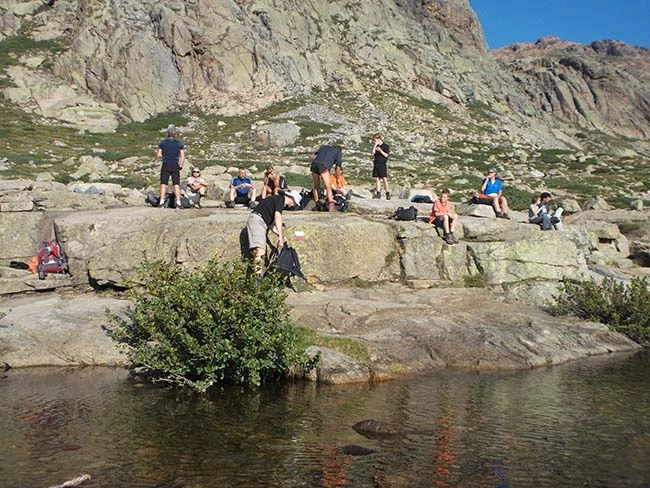 Wandergruppe macht Pause an einem Fluss in den Bergen von Korsika