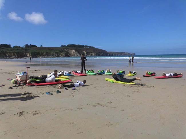 Surfgruppe bekommt erste Übungen am Strand gezeigt