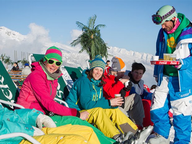 Skigruppe pausiert in Liegestühlen im Skiurlaub Crans Montana in der Schweiz