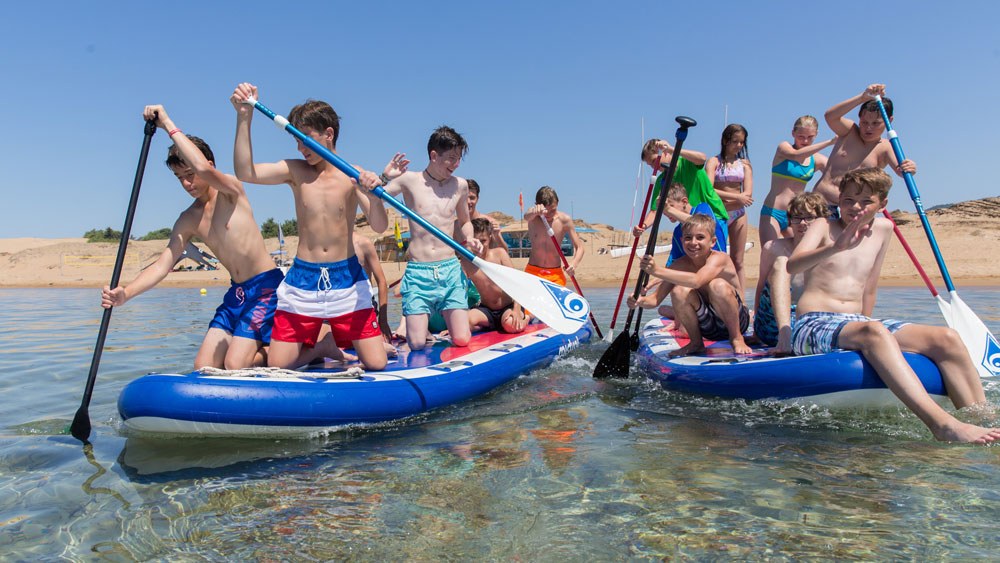 Jugendliche auf Mega-SUPs paddeln im Meer vor Korfu.
