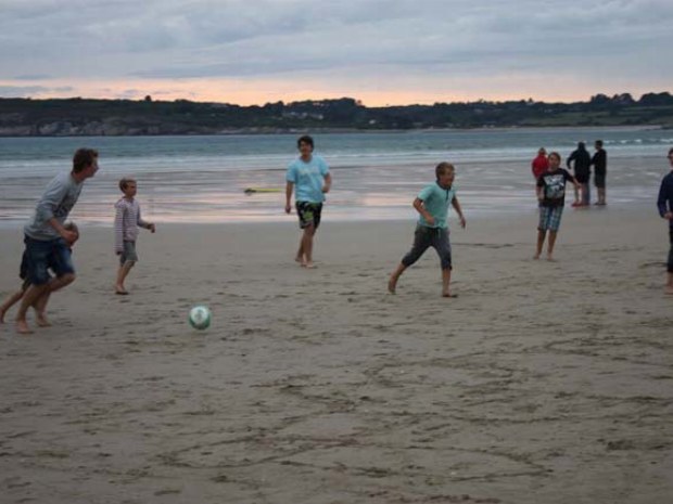 Teenager spielen in der Abenddämmerung Fußball am Strand in der Bretagne