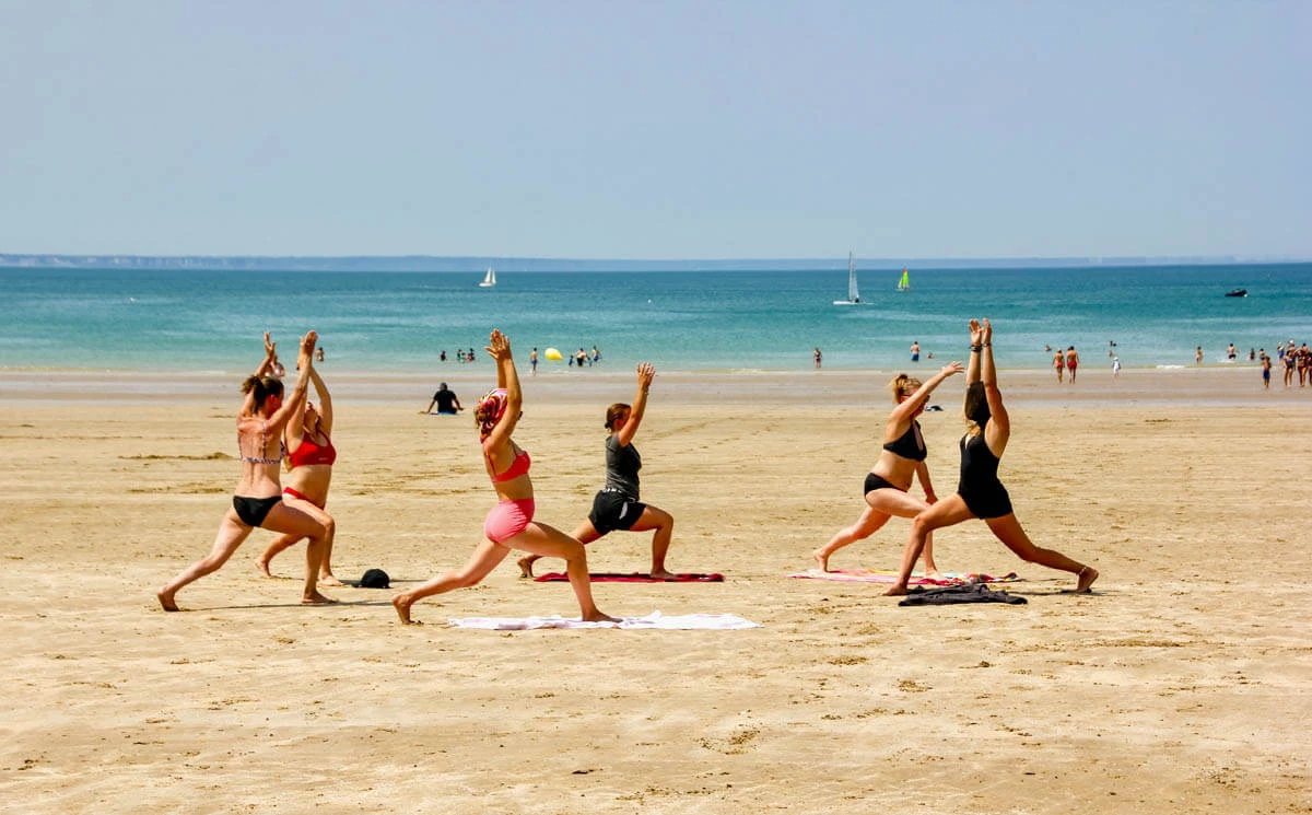 Yoga am Sandstrand in der Gruppe