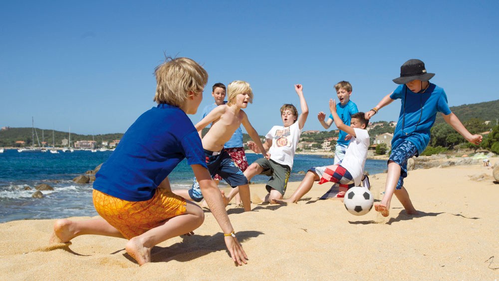 Kinder spielen Fußball am Strand des Sporthotels