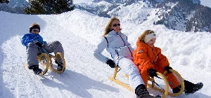 Rodeln mit Kindern und Erwachsenen im Schnee