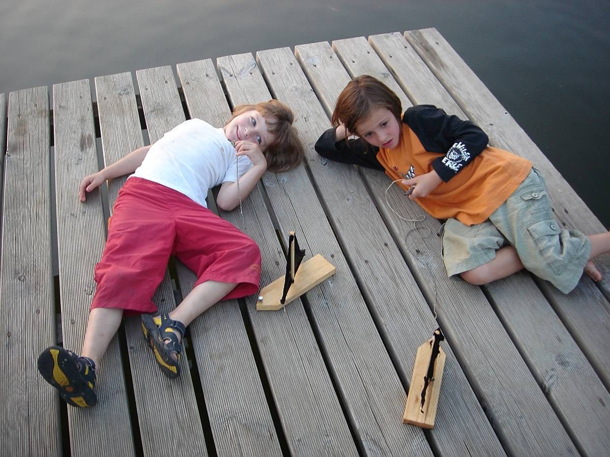 Kinder auf Steg mit Spielzeug Boote