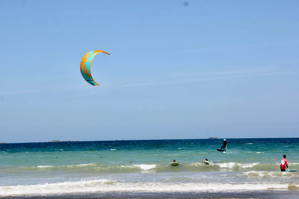 Kiter kitet bei starkem Wind über strandnahes Wasser